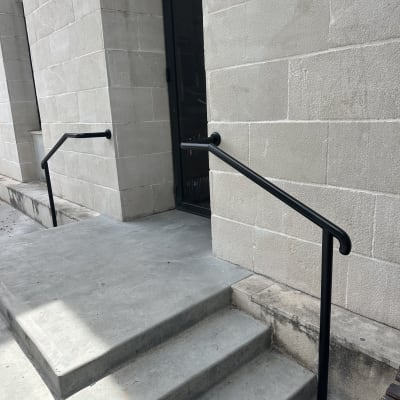 מעקה מתכת שחור ליד מדרגות בטון אפורות
