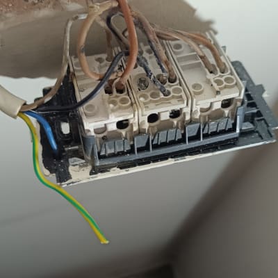 חוטי חשמל מחוברים לתיבת חיבורים בקיר