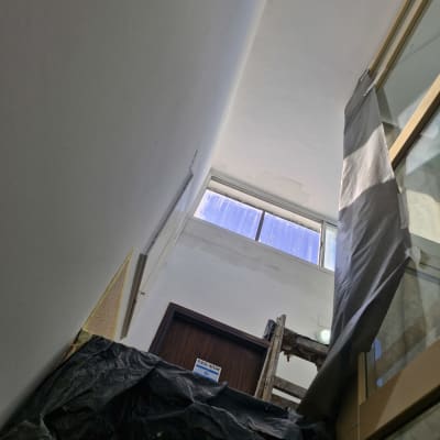 סולם עץ ליד קיר צבוע לבן עם סימני צבע