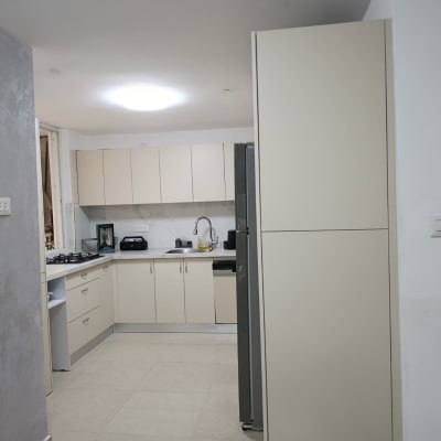 מטבח מודרני עם ארונות בהירים ומכשירי חשמל.