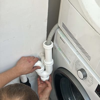 אדם מתקן צינור ליד מכונת כביסה