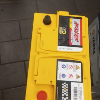 מצבר צהוב עם תוויות אזהרה על רצפה אפורה