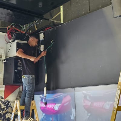 חשמלאי עובד עם כבלים על סולם ליד לוח חשמל