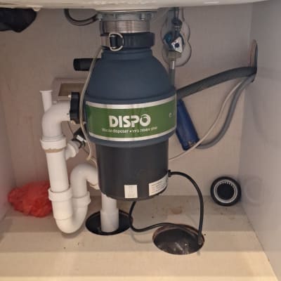 מתקן טוחן אשפה מתחת לכיור עם צינורות חיבור