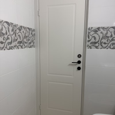 דלת לבנה עם ידית שחורה בחדר אמבטיה