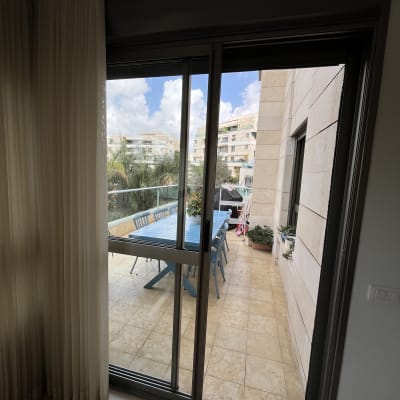 מרפסת עם שולחן וכיסאות, נוף לבניינים ועצים