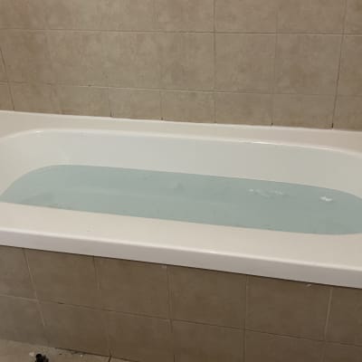 אמבטיה מלאה מים עם ברז מתכת על קיר אריחים