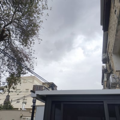 שמיים מעוננים עם עצים ובניינים ברקע