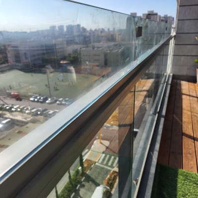 מעקה זכוכית במרפסת עם נוף עירוני ברקע