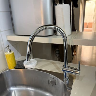 ברז נירוסטה מעל כיור מטבח עם סבון כלים ומתקן נייר מגבת.