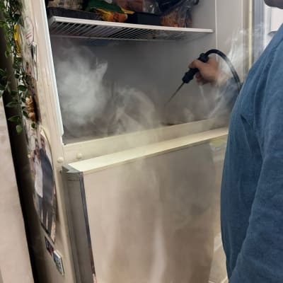 אדם מפשיר מקרר עם מכשיר קיטור