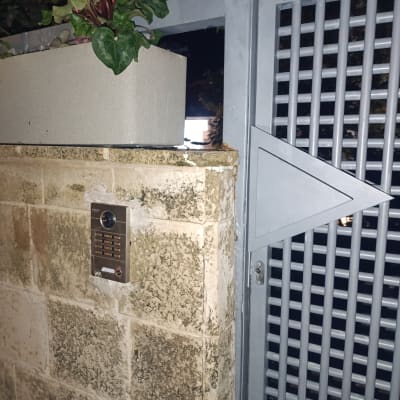 אינטרקום מותקן על קיר אבן ליד שער מתכת