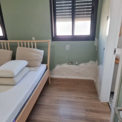 חדר שינה עם קיר צבוע ותיקונים בקיר