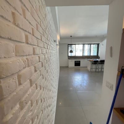 קיר לבנים צבוע בלבן במסדרון מואר