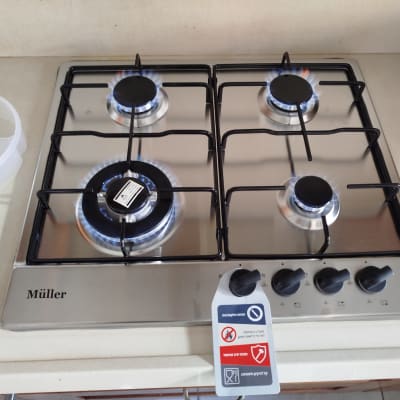 כיריים גז עם ארבעה מבערים דולקים ותווית אזהרה