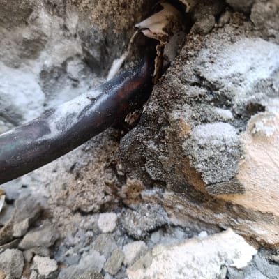 צינור מתכת חשוף בקיר עם טיח מתקלף