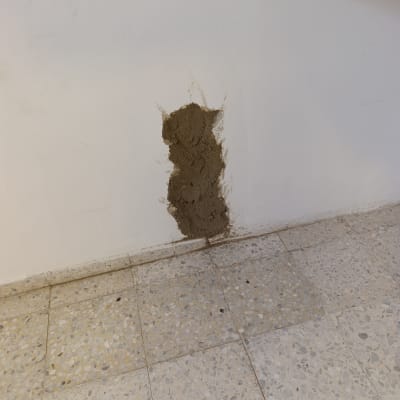 קיר עם תיקון טיח על רצפת אריחים