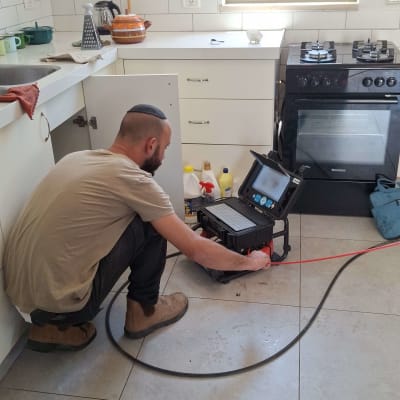 אדם עובד עם מצלמת אינסטלציה במטבח