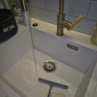 ברז זהב זורם בכיור עם מגב וספוג
