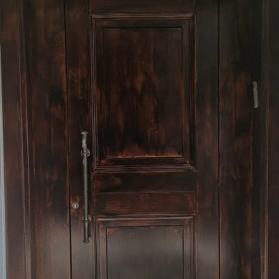 דלת עץ כהה עם ידית מתכת על רקע קיר בהיר
