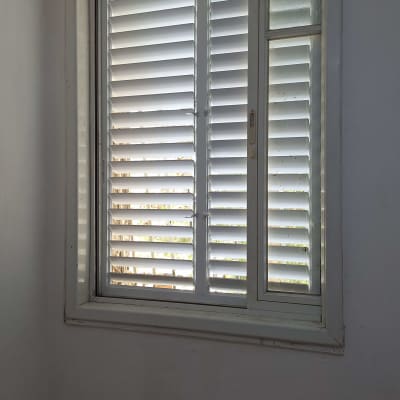 תריסים לבנים סגורים על חלון עם מסגרת לבנה