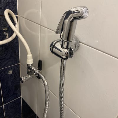 ברז ידני עם צינור מתכת על קיר קרמיקה