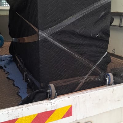 חפץ עטוף בשמיכה שחורה על גלגלים בתוך רכב הובלה