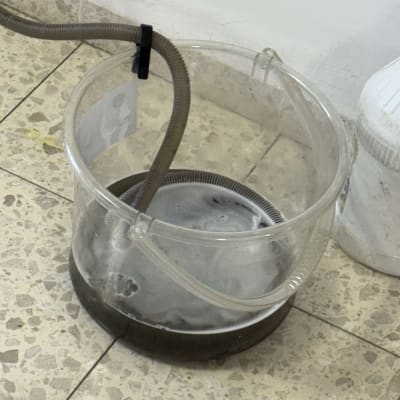 דלי עם צינור על רצפה מרוצפת