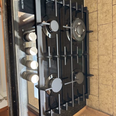 כיריים גז עם כפתורים על משטח מטבח כהה