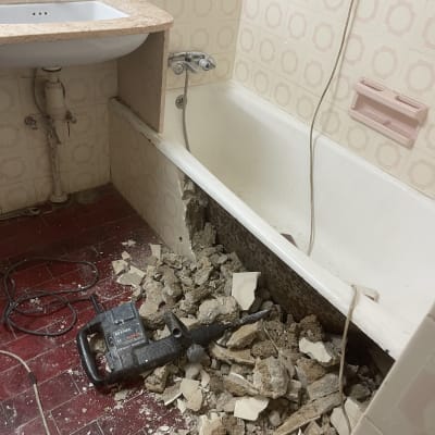 שיפוץ אמבטיה עם קיר שבור וכלי עבודה על הרצפה
