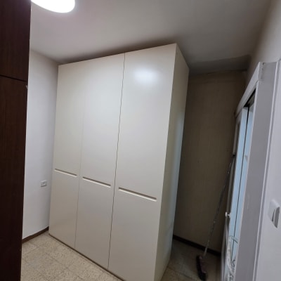 ארון לבן גדול בחדר עם מטאטא בצד