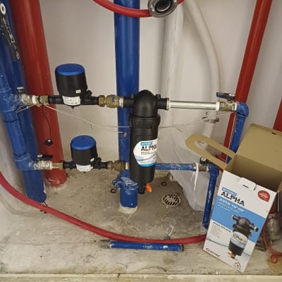 מסנן מים מותקן על צינורות כחולים ואדומים