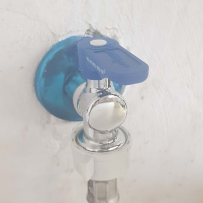 ברז מים עם ידית כחולה וצינור מחובר