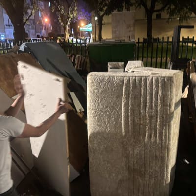 אדם מזיז לוח עץ ליד ערימת רהיטים ברחוב