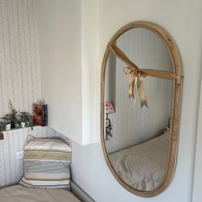 מראה אובלית תלויה על הקיר עם מסגרת עץ