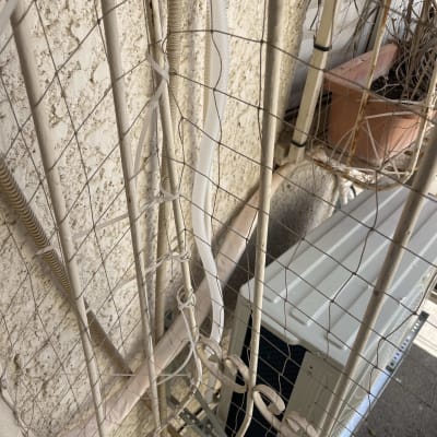 יחידת מיזוג אוויר מותקנת על קיר חיצוני עם צינורות וחוטים.