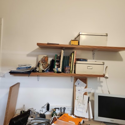 מדף עם ספרים, קופסאות ומסך מחשב על שולחן עבודה