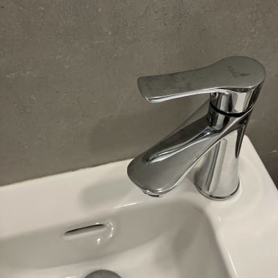 ברז כרום על כיור לבן עם פתח ניקוז