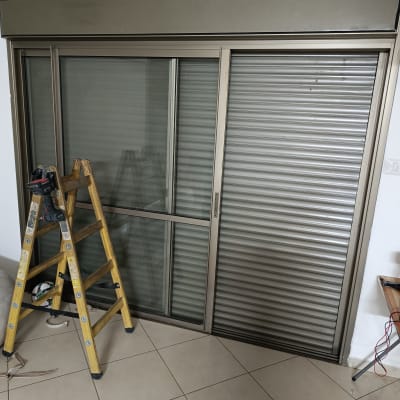 תריס מתכת סגור ליד חלון זכוכית עם סולם עץ