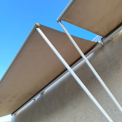 שני סוככים חומים מחוברים לקיר עם מוטות לבנים