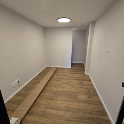 חדר ריק עם רצפת עץ ולוח קרטון על הרצפה