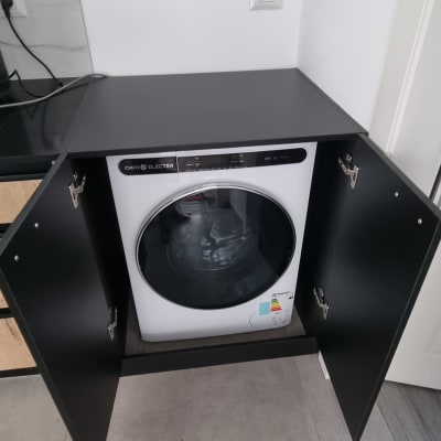 מכונת כביסה בתוך ארון פתוח עם דלתות שחורות