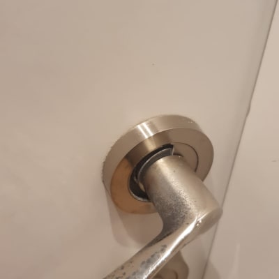 ידית דלת מתכתית על דלת לבנה