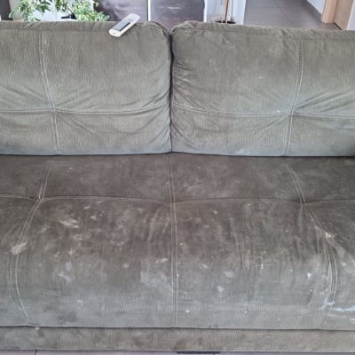 ספה ירוקה עם כתמים, כלי ניקוי בצד