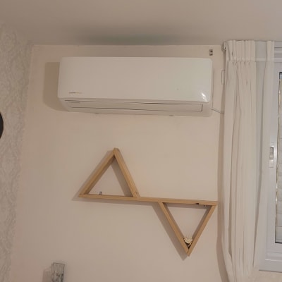 מזגן מותקן על קיר בחדר עם מדף עץ