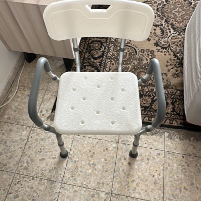 כיסא פלסטיק עם ידיות מתכת על רצפה מרוצפת