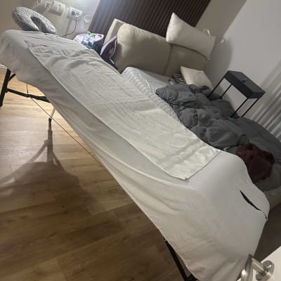 מיטת עיסוי עם סדין לבן בחדר מואר