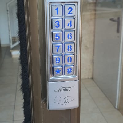 לוח מקשים מתכתי עם מספרים כחולים על דלת