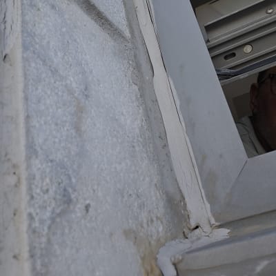 סדקים בקיר ליד חלון עם סימני רטיבות