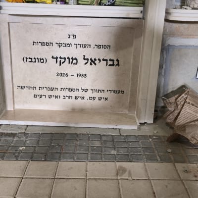 מצבה עם כיתוב בעברית ופרחים מסביב